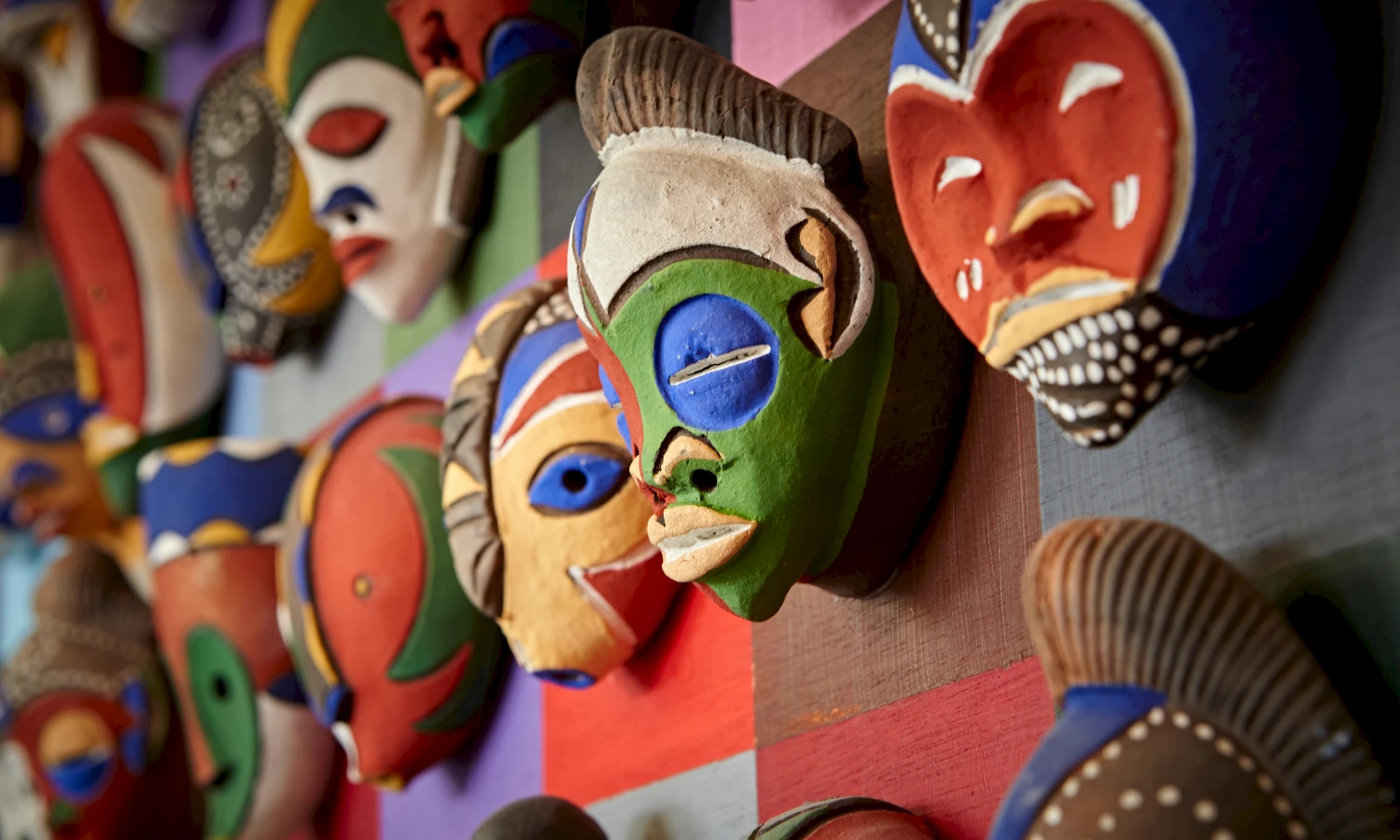 gekleurde Afrikaanse maskers hangen aan kleurrijke wand